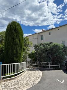 a white building with a white fence and trees at Apartman Karla in Selce