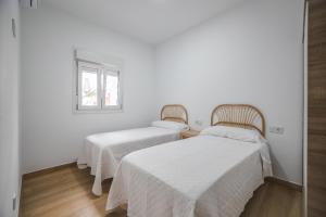 Dos camas en una habitación con paredes blancas. en Patio Cuarenta Bajo, en Algeciras 1 foto más