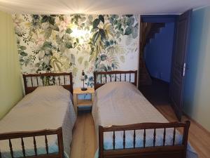 two twin beds in a room with a wallpaper at Le sécadou in Montirat