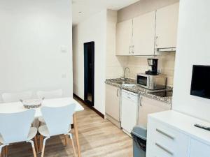 a kitchen with white cabinets and a table and chairs at Sky 503 by CONFORTSKY in Pas de la Casa