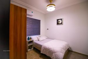 a bedroom with a white bed and a window at Cozy Luxury - East Legon Apt - WiFi, Netflix & AC in Accra