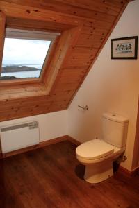 a bathroom with a toilet and a window at Heather Cottage in Lairg