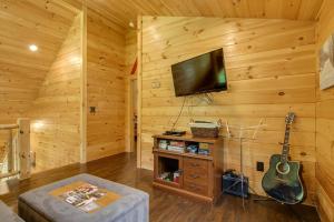 a living room with a flat screen tv and a guitar at Londonderry Chalet with Deck, Fire Pit and Views! in Londonderry