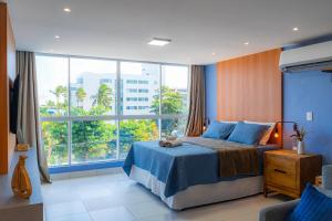 a bedroom with a blue bed and a large window at Costa Serena Flats - Ponta de Campina in Cabedelo +113 photos