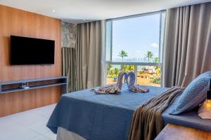 a hotel room with a bed and a flat screen tv at Costa Serena Flats - Ponta de Campina in Cabedelo