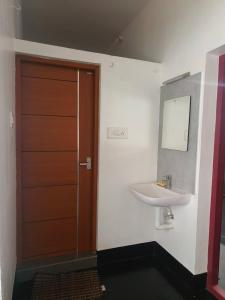 a bathroom with a sink and a wooden door at Palm Villa in Trichūr