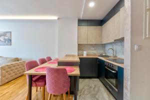 a kitchen with a wooden table and pink chairs at Vip Bogic 79 in Zlatibor