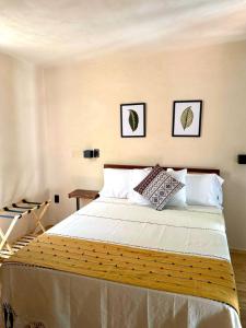 a bedroom with a large bed with two pictures on the wall at Casa Yag in Brisas de Zicatela