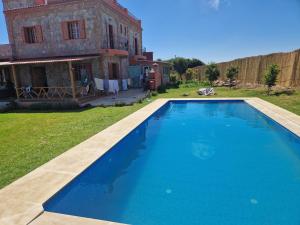 a large blue swimming pool in front of a house at MesklilHouse in Asilah