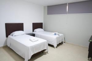 two beds in a room with white sheets at Hotel y Restaurante BCB La Jagua in La Jagua de Ibirico +19 photos