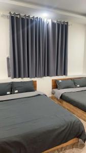 two beds in a room with black curtains at Ciel 9601 Home in Da Lat