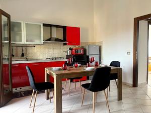 une cuisine avec des placards rouges et une table en bois avec des chaises dans l'établissement La Casetta di Lally, à Cabras