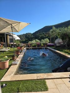 two people are swimming in a swimming pool at Gîte SPA Piscine Cévennes in Saint-André-de-Majencoules
