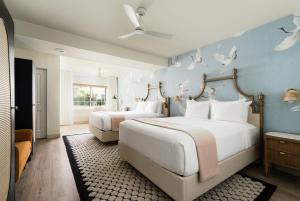 two beds in a bedroom with birds on the wall at The Milo in Santa Barbara