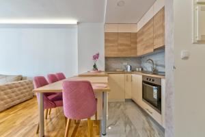 a kitchen with a wooden table and pink chairs at Vip Bogic 58 in Zlatibor