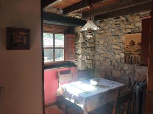a dining room with a table and a stone wall at Ribera del Sella III in Dego