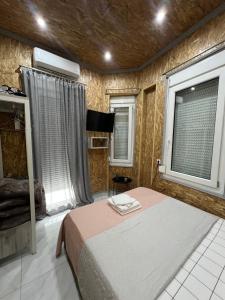 a bedroom with a bed and a tv and two windows at City Corner Stay in Kavala
