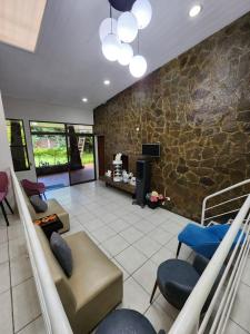 a living room with couches and chairs and a stone wall at Mochila Urban1 in San Salvador