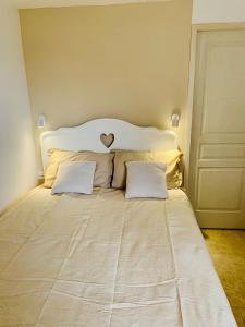 a white bed with two pillows and a heart above it at Appartement 2 chambres 2 salles de bains haute ville in Porto-Vecchio
