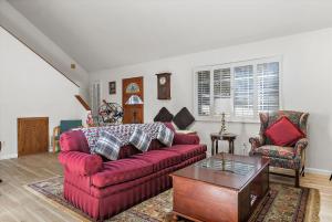 Una sala de estar con un sofá rojo y una mesa. en Holly Hill Cottage, en Cambria