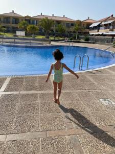 Ein kleines Mädchen, das am Pool vorbeigeht. in der Unterkunft Atlantico breeze in Costa Del Silencio