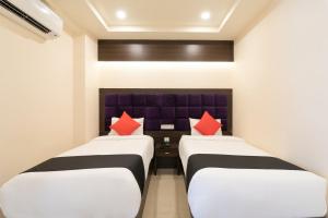 two beds in a hotel room with red pillows at Capital O Seatree in Visakhapatnam