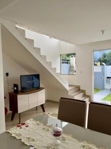 ein Wohnzimmer mit einer Treppe und einem Tisch in der Unterkunft Casa prox. a praia do Campeche in Florianópolis