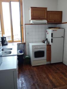 a kitchen with a white stove and a refrigerator at Poterie d'Art in Embrun