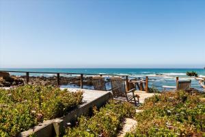 eine Terrasse mit Stühlen und das Meer im Hintergrund in der Unterkunft Sunset Sanctuary Oceanfront Luxury Monthly Newly remodeled in Cambria