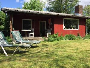 a red house with two chairs in front of it at Schwedenhaeuschen-am-See-einfach-Lagom in Bistensee