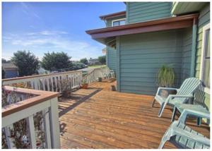 a wooden deck with two chairs on a house at Casa De La Mar in Cambria