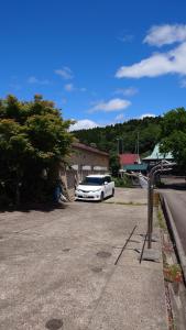 ein weißes Auto auf einem Parkplatz geparkt in der Unterkunft 白神山地の麓でヤギのいるゲストハウス　あわじ商店 in Fujisato