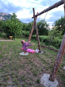 a little girl sitting on a swing in a field at Konak -Guest house -Ramonda Serbika in Niš