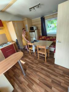 a woman is standing in a kitchen with a table at mobil home 4 personne 2 chambre vu lac a condes in Condes +2 photos