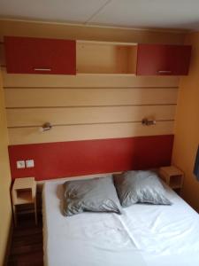 a bedroom with a bed with a red headboard at mobil home 4 personne 2 chambre vu lac a condes in Condes