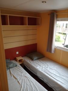 two beds in a small room with a window at mobil home 4 personne 2 chambre vu lac a condes in Condes