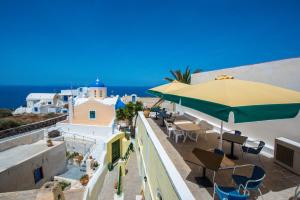 un balcón con sombrilla, sillas y el océano en Christos Apartments Oia, en Oia