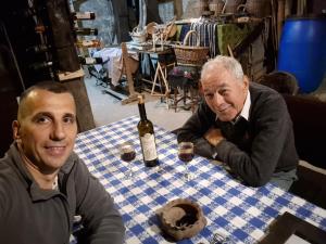 two men sitting at a table with a bottle of wine at Konak -Guest house -Ramonda Serbika in Niš