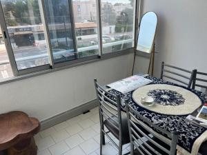 a dining room with a table and chairs and windows at Bel appartement proche des plages in Sète