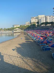 a bunch of umbrellas and chairs on a beach at Shtepipushimi23 Rana e Hedhun in Shëngjin