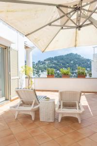 un patio con dos sillas y una sombrilla en CapriGetaway - La Rosa Bianca, en Capri