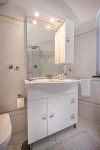 Un baño blanco con lavabo y espejo. en CapriGetaway - La Rosa Bianca, en Capri