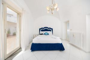 1 dormitorio blanco con 1 cama con cabecero azul en CapriGetaway - La Rosa Bianca, en Capri
