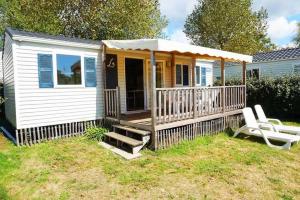 una casa pequeña con porche y 2 sillas blancas en Camping 4 étoiles - Parc aquatique - eeiaei, en Givrand