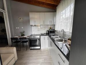 a kitchen with white cabinets and a sink and a table at Nikos House by Delta Hospitality in Ofrínion