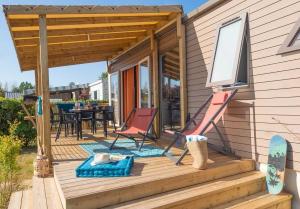 ein Haus mit einer Terrasse mit Stühlen und einem Tisch in der Unterkunft Camping 4 étoiles - Parc aquatique - eeic0a in La Tranche-sur-Mer