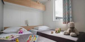 een slaapkamer met twee bedden met poppen en speelgoed erop bij Camping 5 étoiles - Parc aquatique - eeiaid in Pénestin