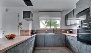 Una cocina con armarios de madera y un fregadero y una ventana. en Superbe maison avec piscine privée, en Bénodet