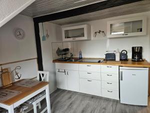 a kitchen with white cabinets and a sink and a table at Susan's ole Schoolhus in Fehmarn