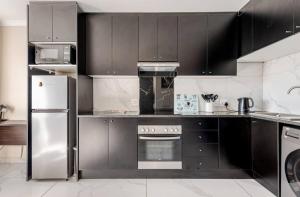 a kitchen with black cabinets and a stainless steel refrigerator at Cozy loft with swimming pool in Johannesburg